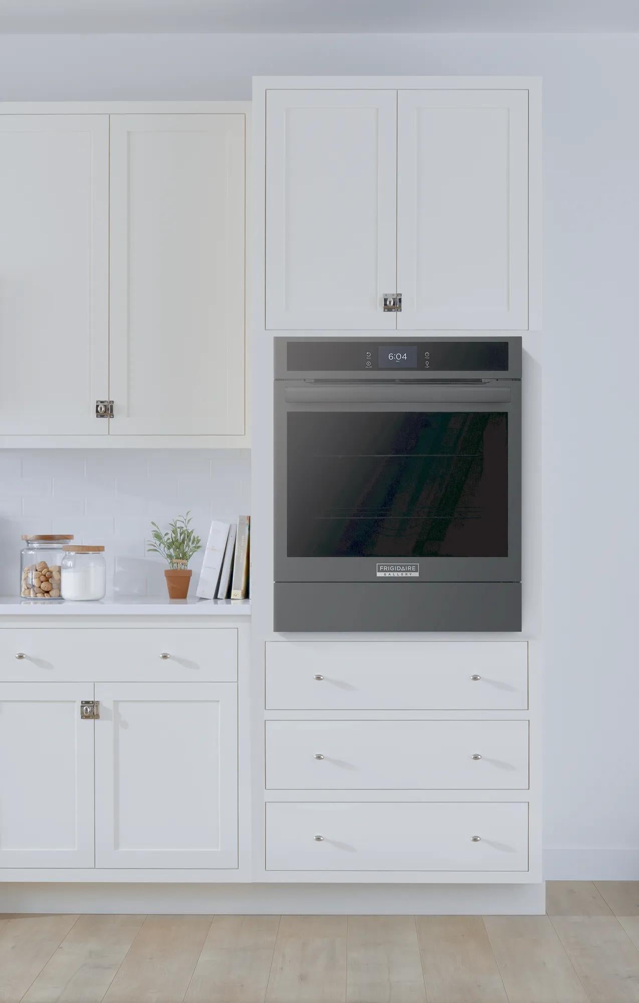Built-in black electric wall oven with digital controls installed in modern white kitchen cabinetry for home improvement.