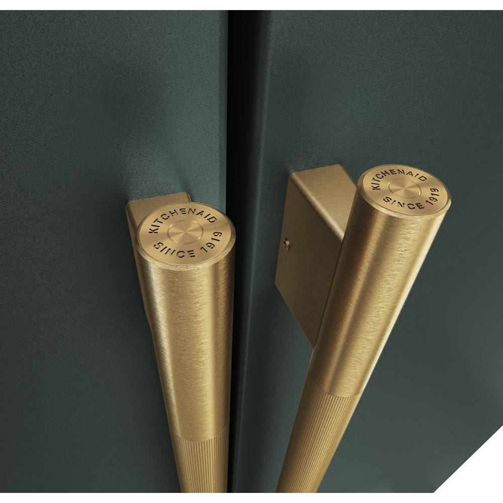 Close-up of brushed gold French door handles with engraved KitchenAid logo on dark green refrigerator doors
