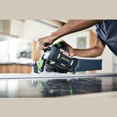Person guiding Festool cordless track saw with kickback stop on guide rail for home improvement and power tools