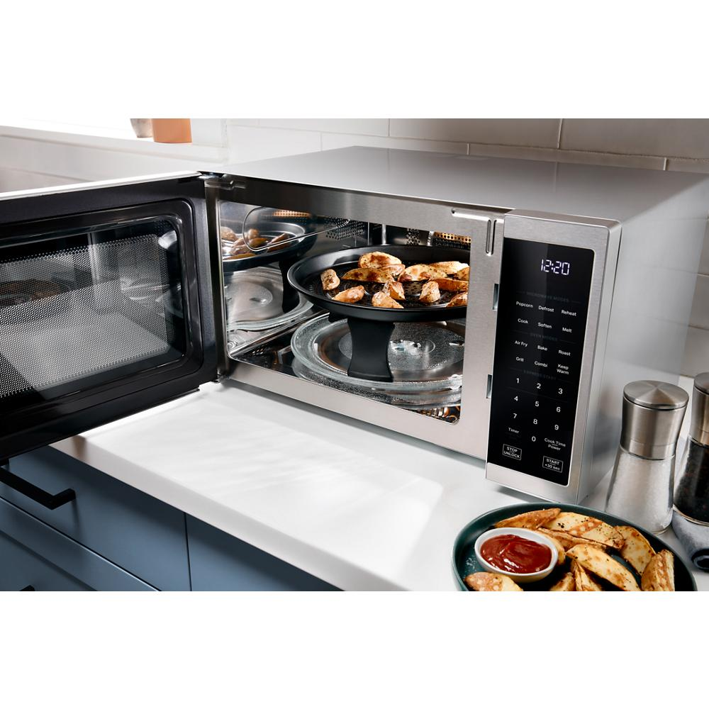 Stainless steel multifunctional countertop microwave with air fry and grill modes cooking chicken wings in modern kitchen