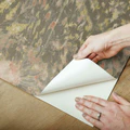 Hand applying taupe peel and stick wallpaper with subtle dandelion design for easy home improvement projects