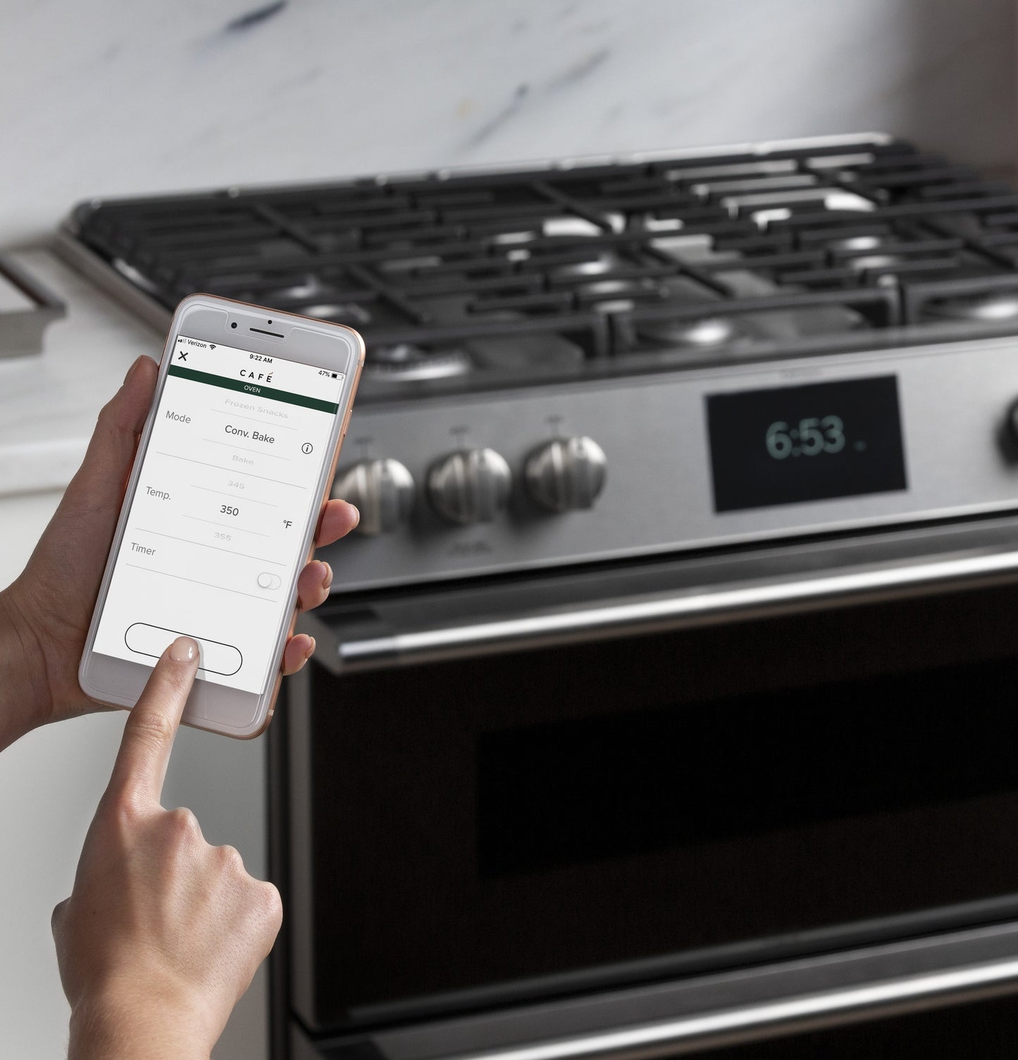 User controlling a platinum glass smart gas range with convection oven using a mobile app for home improvement.