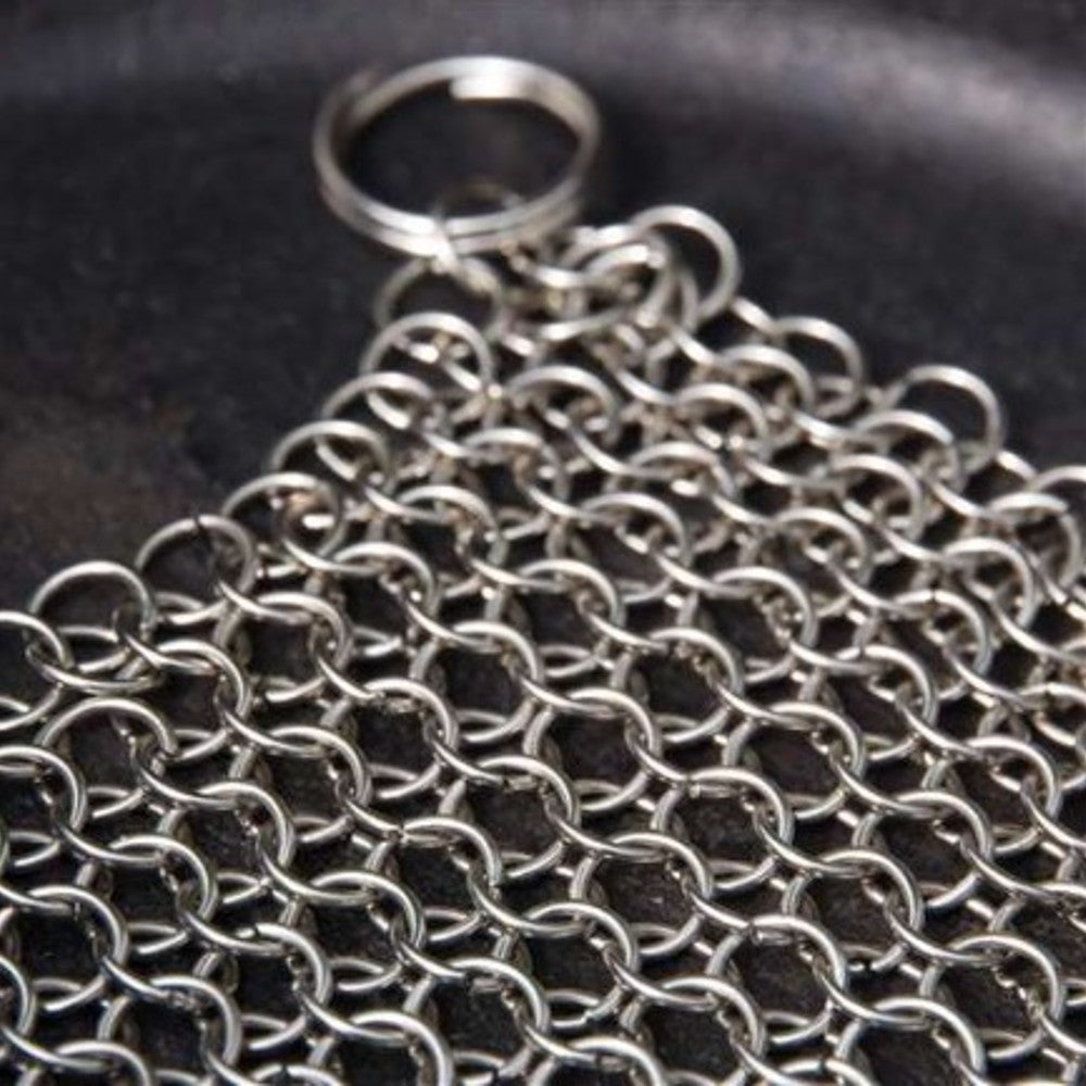 Close-up of stainless steel chainmail cleaner with keyring on cast iron skillet for kitchenware and home tools under $50