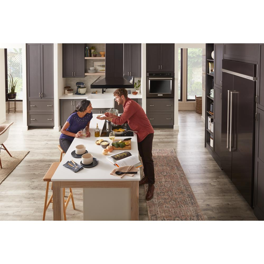 Modern kitchen with dark cabinetry, large island, stainless steel appliances, and 36-inch island-mount canopy hood from KitchenAid collection
