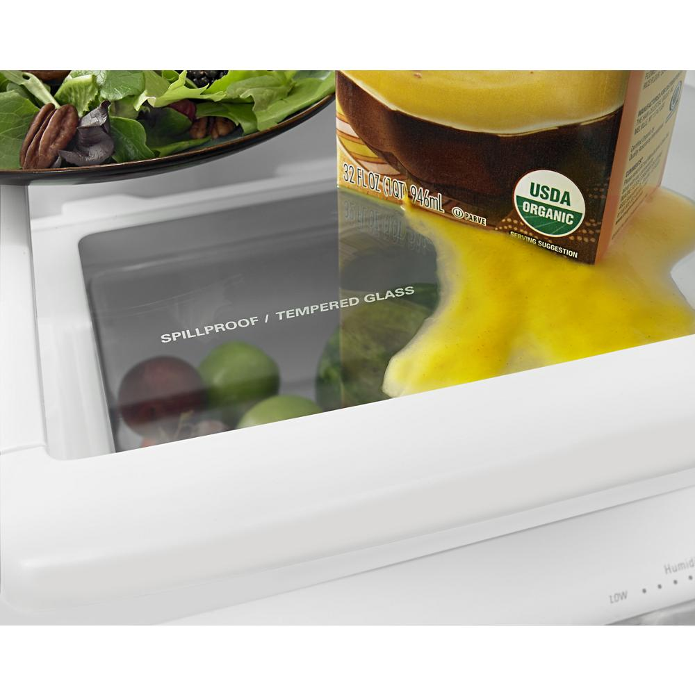 Close-up of spillproof tempered glass shelf in a refrigerator containing fresh salad and a spilled juice carton