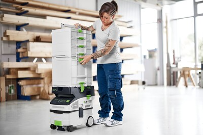 Person stacking modular white and green Festool Sortainer drawers for workshop organization and tool storage accessories