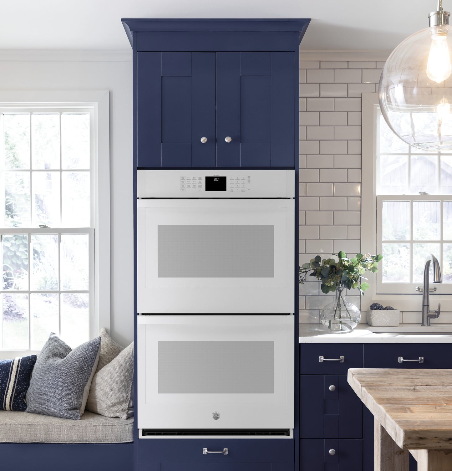 White built-in double wall oven integrated into navy blue cabinetry in modern kitchen and appliances collection