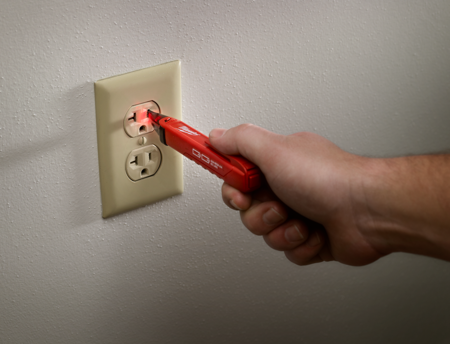 Handheld red voltage detector with LED light testing power at a residential electrical outlet in home improvement tools collections