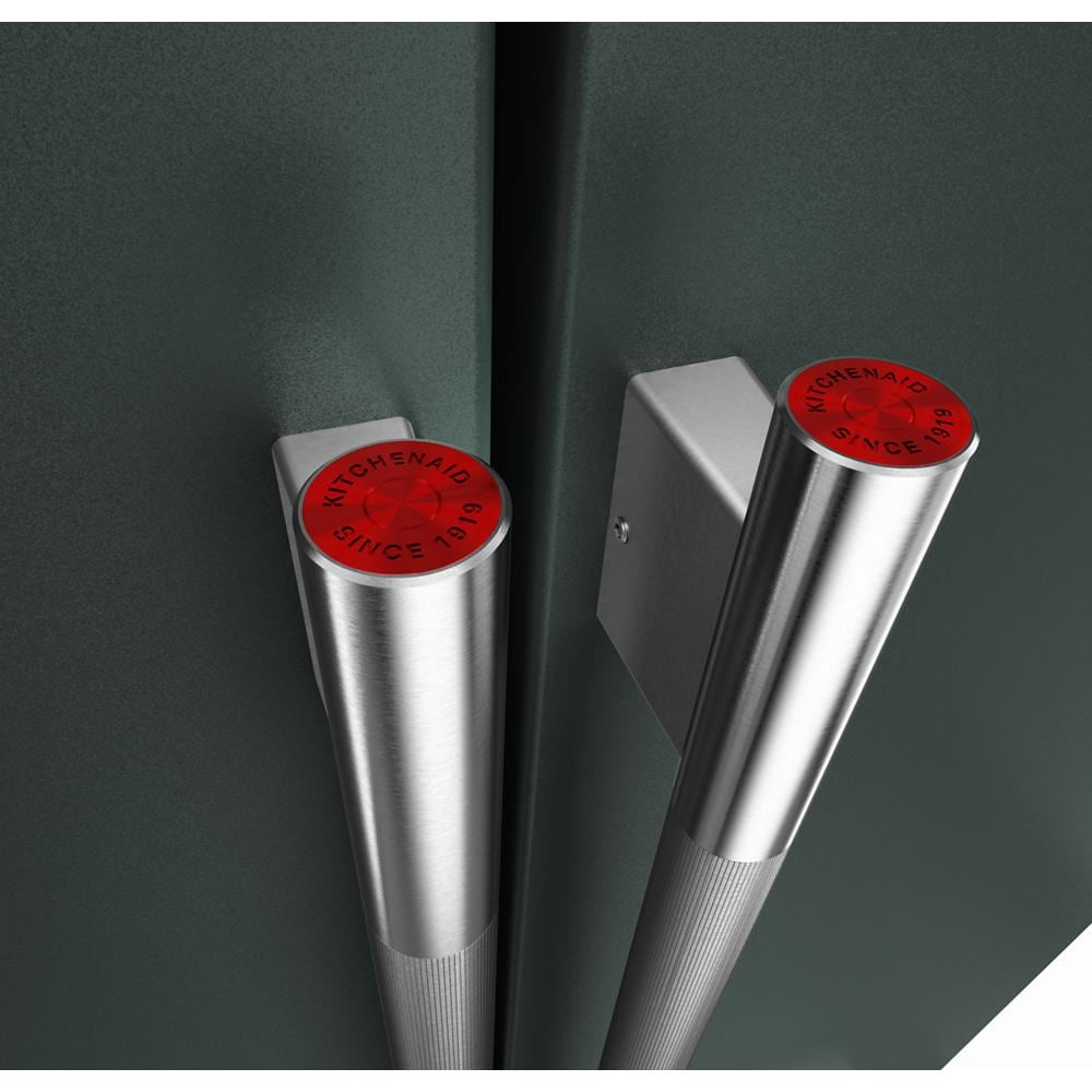 Close-up of brushed stainless steel handles with red KitchenAid logo caps on a dark gray French door refrigerator