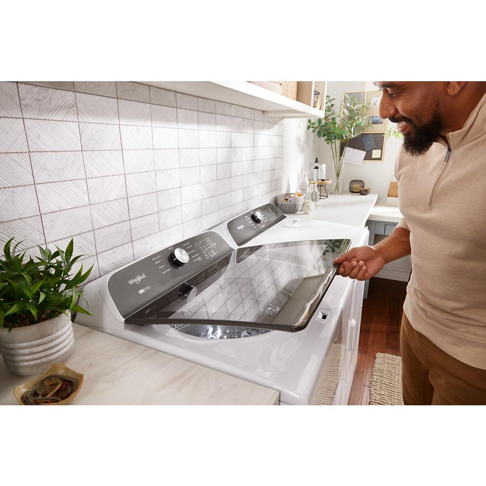 Man loading white top load Whirlpool washer with control dial in bright laundry room for home improvement tasks
