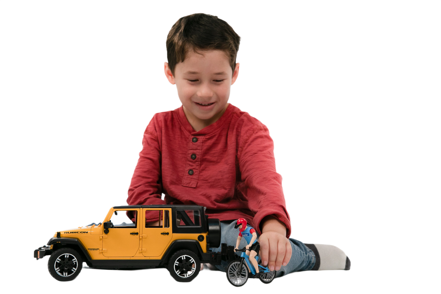 Young boy in red shirt playing with yellow Bruder Jeep Wrangler Rubicon Unlimited toy and cyclist figure from Toys & Games collection