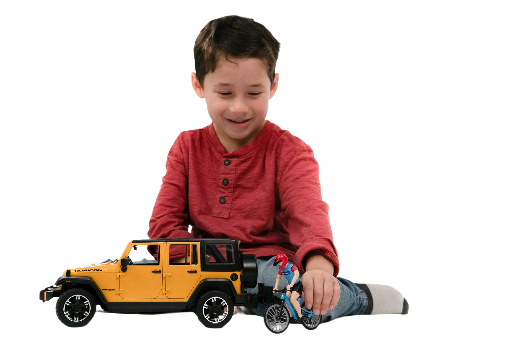 Young boy in red shirt playing with yellow Bruder Jeep Wrangler Rubicon Unlimited toy and cyclist figure from Toys & Games collection