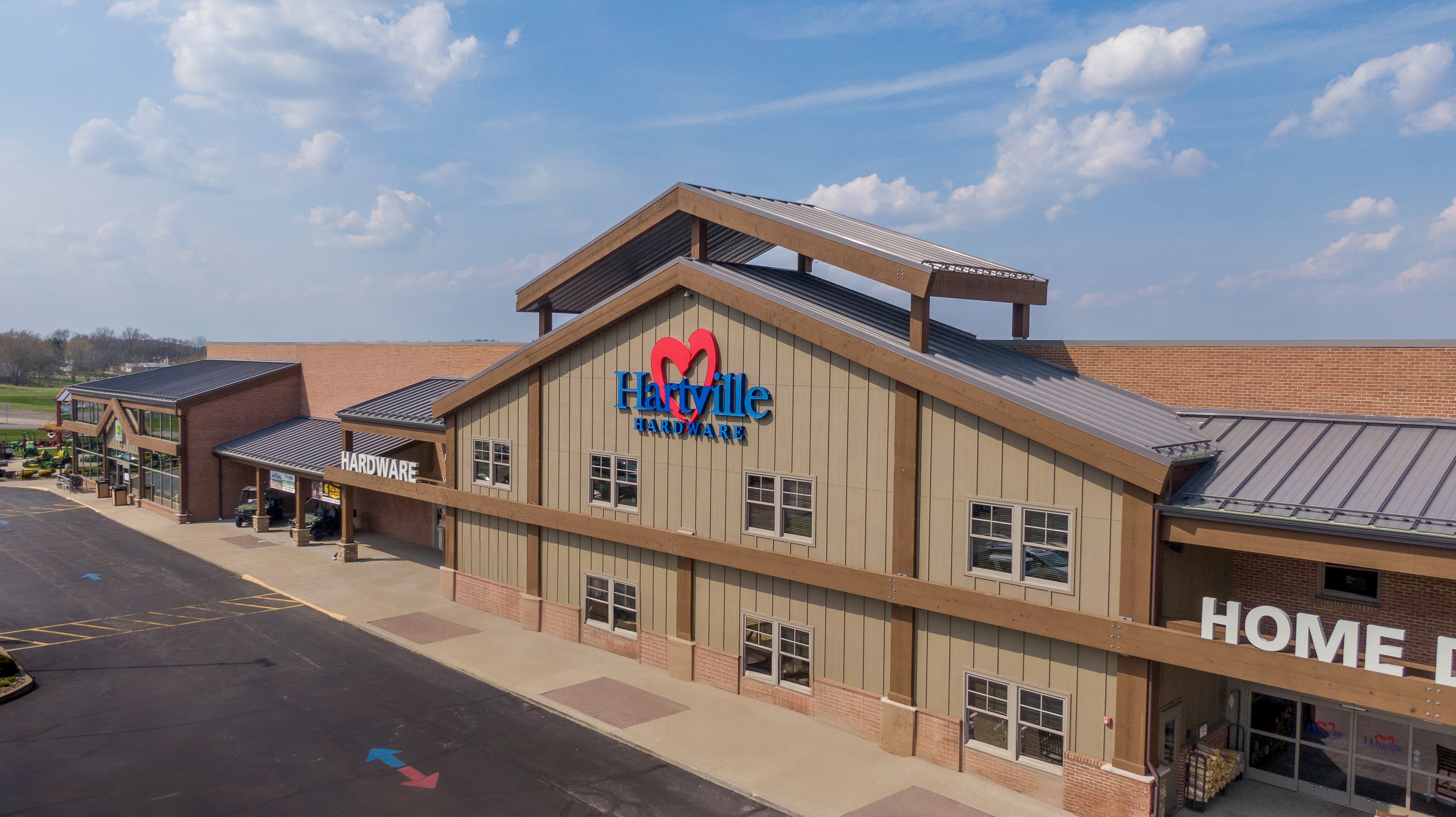 Exterior view of a Hartville Hardware building with a metal roof under a partly cloudy sky, showcasing home improvement and hardware store facilities.