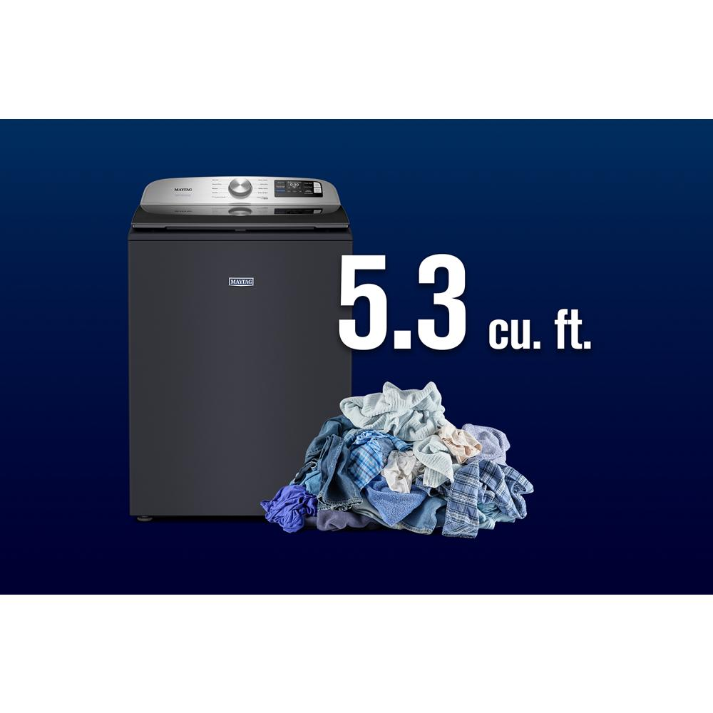 Dark gray top load washer with digital controls and a pile of laundry, part of washers and appliances collection.
