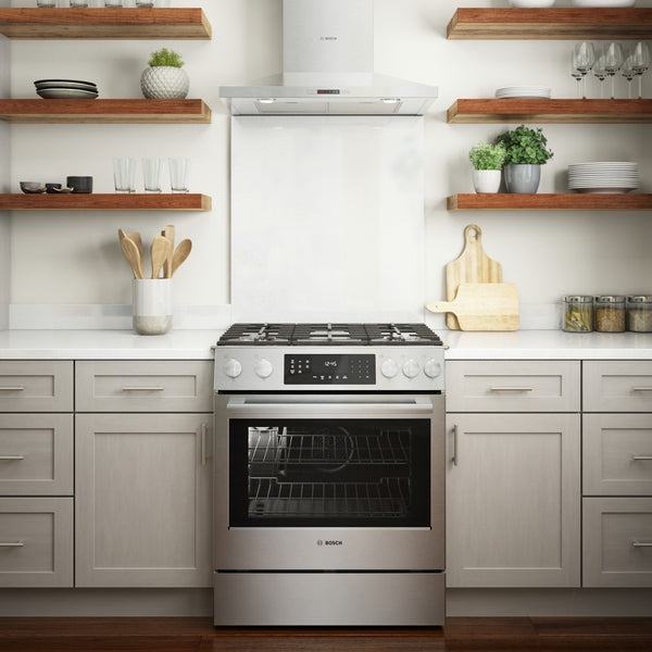 stainless steel gas range with digital display and metal knobs installed in modern kitchen with open shelving