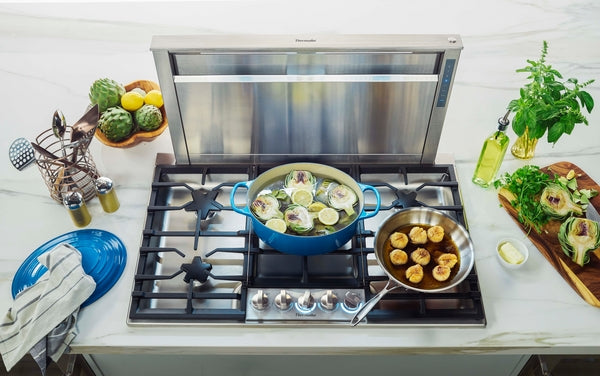 36-inch stainless steel gas cooktop with star burner cooking lemon artichokes and sautéed scallops in modern kitchen setting
