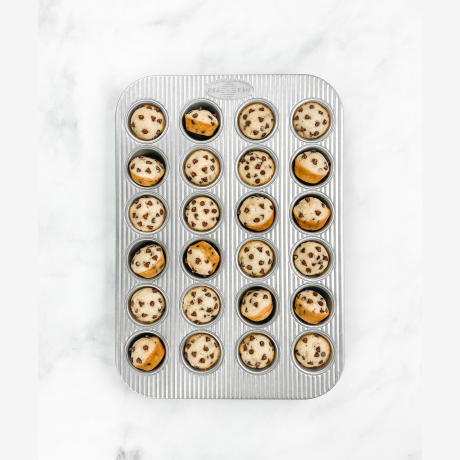 24-cup mini muffin pan with non-stick surface containing partially baked chocolate chip muffins in kitchenware collections under $50