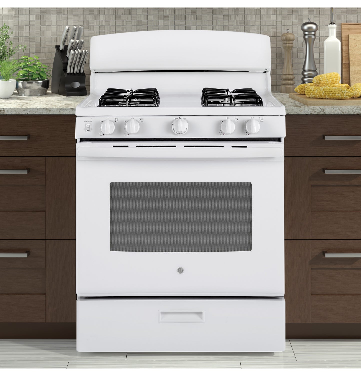 White free-standing gas range with four burners and front control knobs in modern kitchen setting with wooden cabinets
