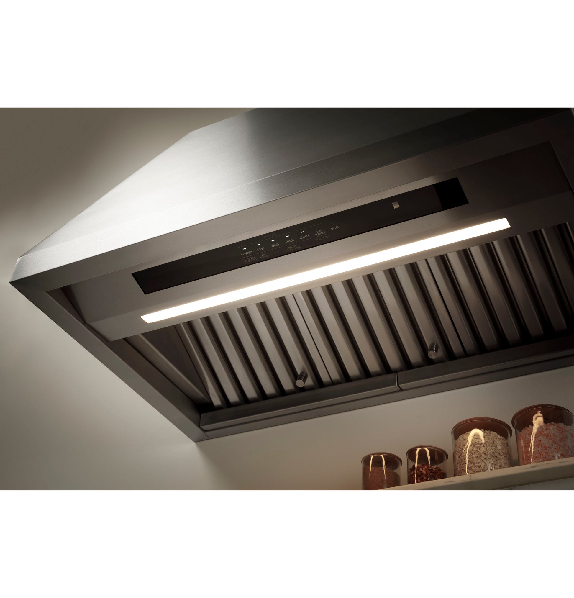 Close-up of modern stainless steel range hood with built-in light and metal baffle filters in kitchen appliances setting