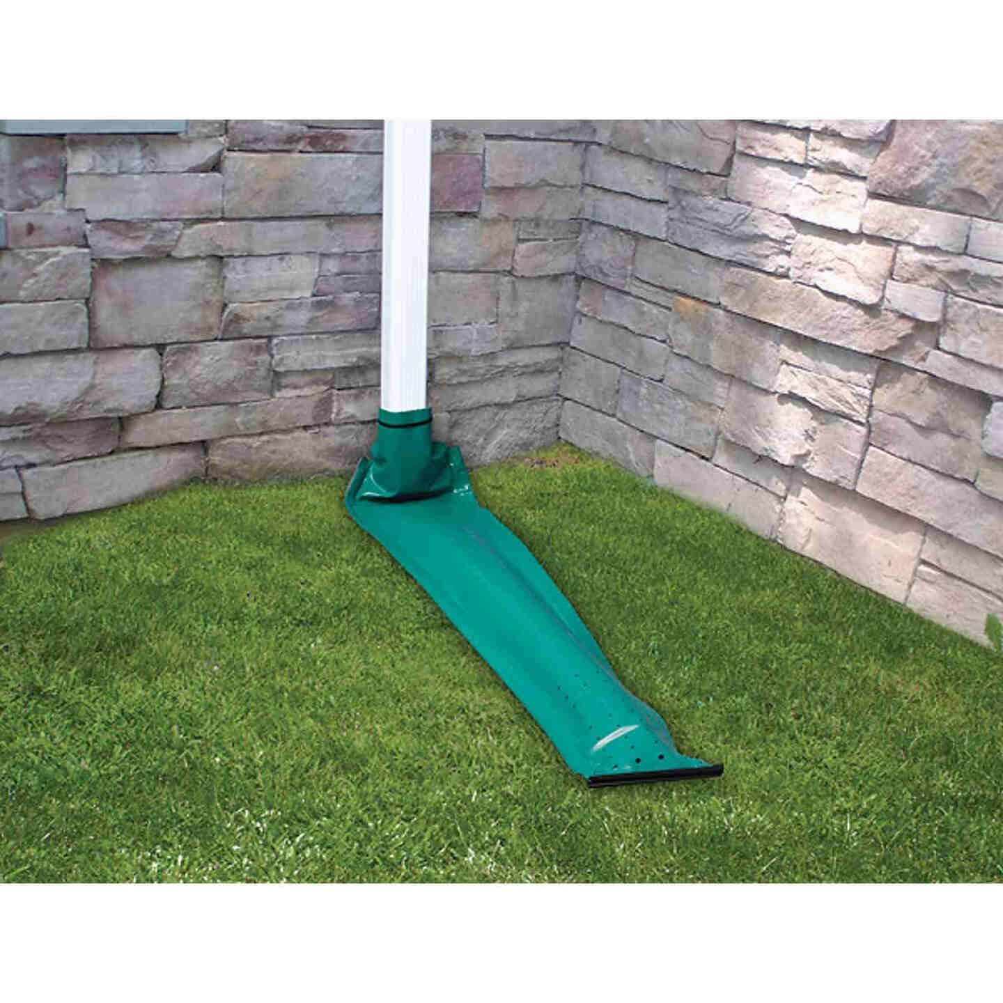 Green plastic drain-away extender attached to downspout directing water onto grass for home improvement use