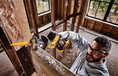 Man using DEWALT cordless reciprocating saw for cutting wood in a home improvement construction setting
