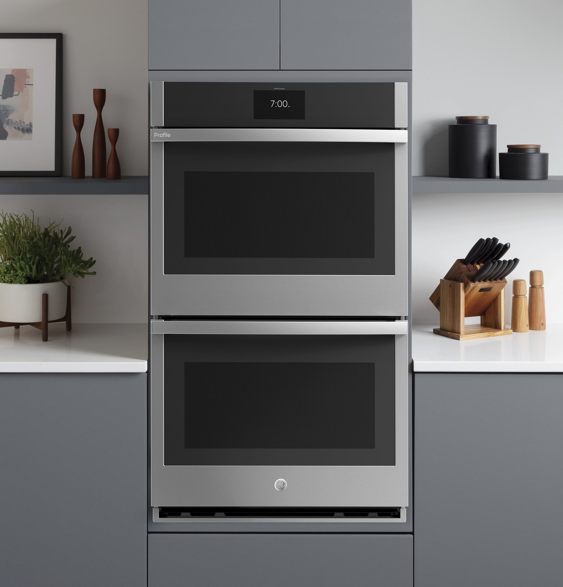 Built-in stainless steel convection double wall oven in modern kitchen with gray cabinets and countertop decor
