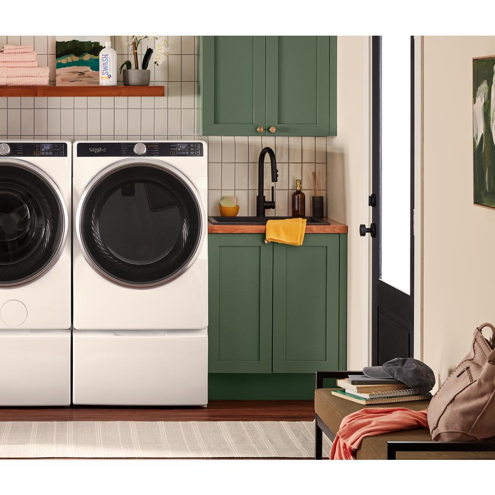White smart front load gas dryer with large black door and digital panel in modern laundry room setting