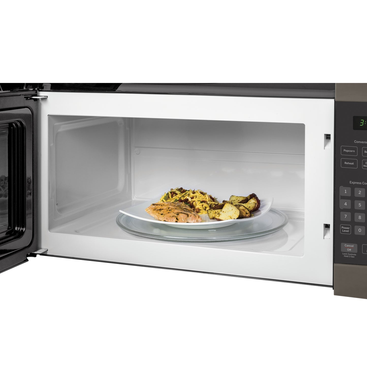 Open over-the-range microwave with white interior and plate of seasoned cooked food inside from kitchen appliances collection