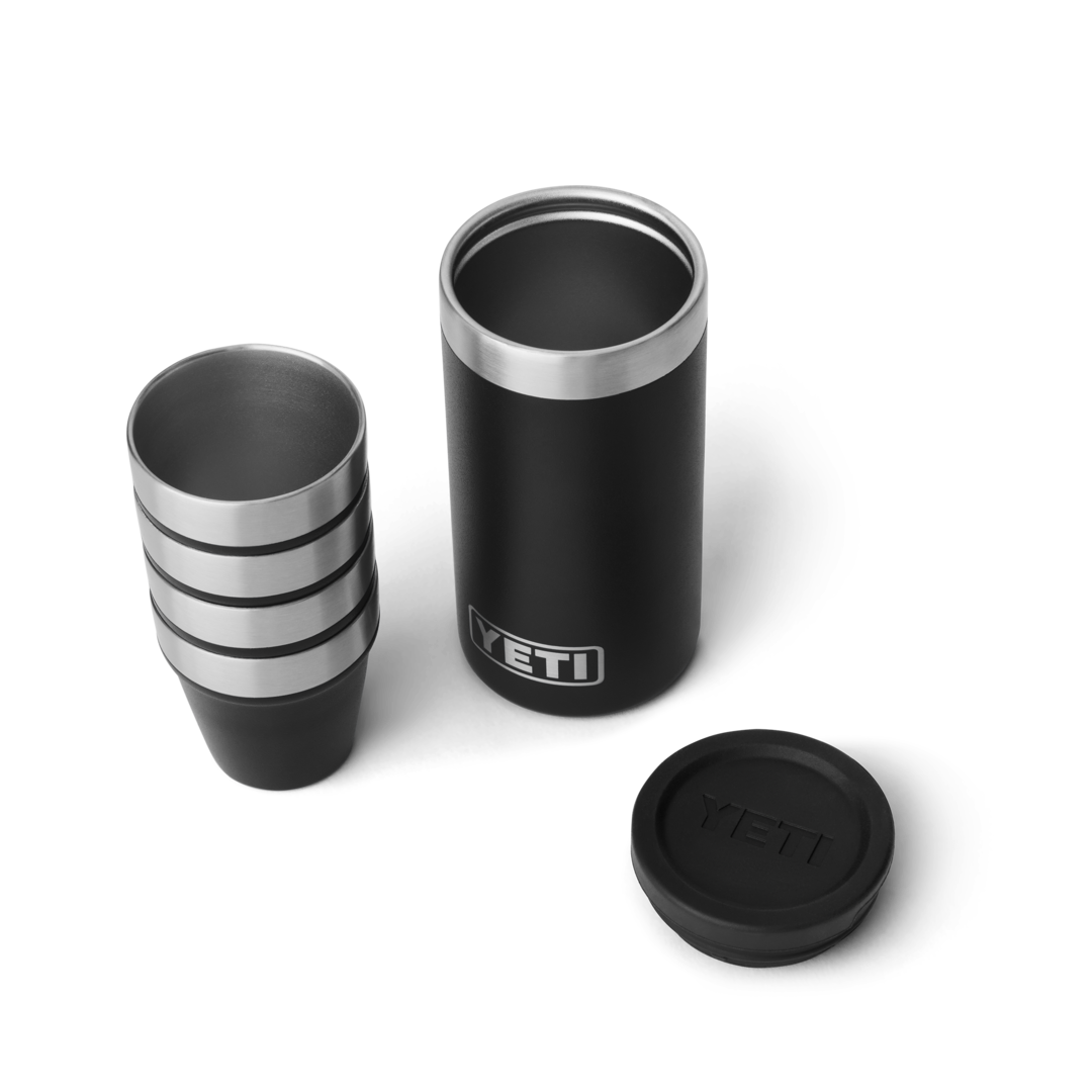 Stacked black stainless steel shot glasses next to a matching insulated carrying case for durable outdoor drinkware use