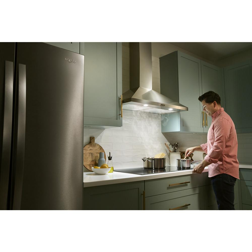 Modern kitchen with stainless steel wall mount range hood venting steam from stovetop cooking in home improvement setting