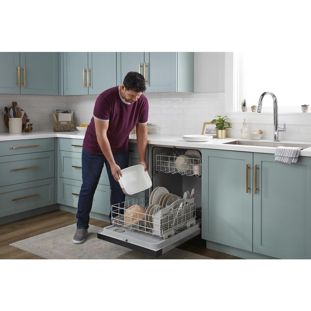 Man loading white dishes into open ENERGY STAR® certified quiet dishwasher in modern kitchen with blue cabinetry