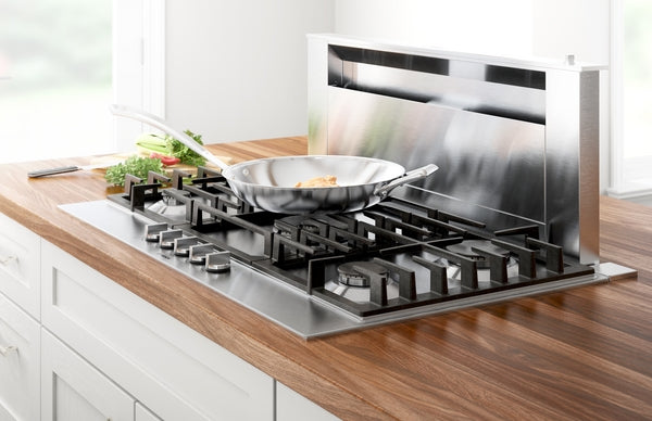 Stainless steel 36-inch gas cooktop with five burners and cast iron grates integrated into wooden countertop kitchen setting