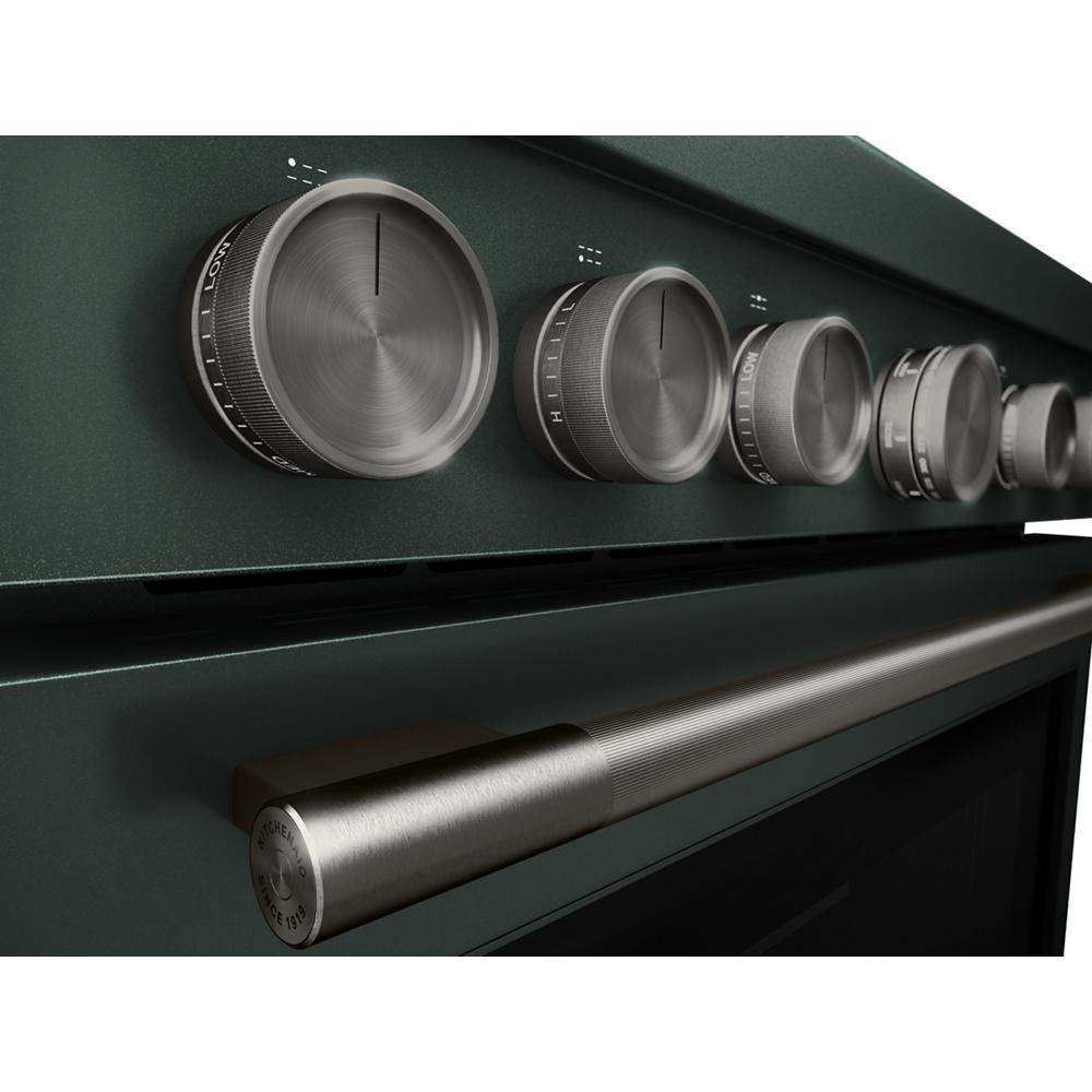 Close-up of stainless steel control knobs and brushed metal handle on dark green commercial-style gas range from KitchenAid collection