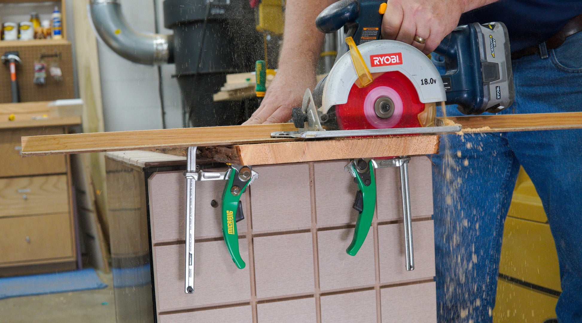 Green-handled dovetail ratchet clamps holding wood on a workbench during a wooden cutting home improvement task