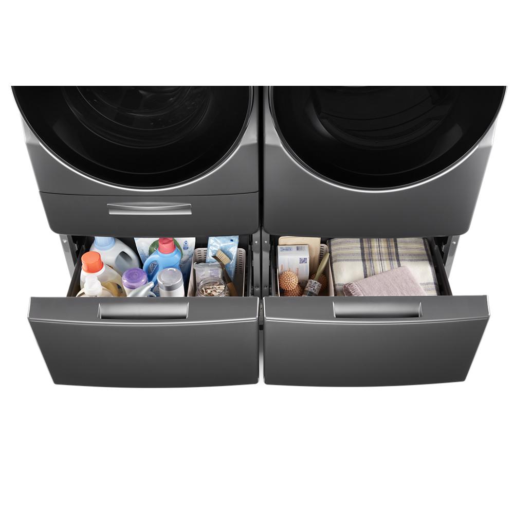 Two black storage drawers beneath front load washer and dryer holding laundry supplies and linens in appliance parts collection