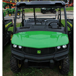 Front view of a John Deere utility vehicle featuring aggressive tires and durable chassis on grass in equipment lot