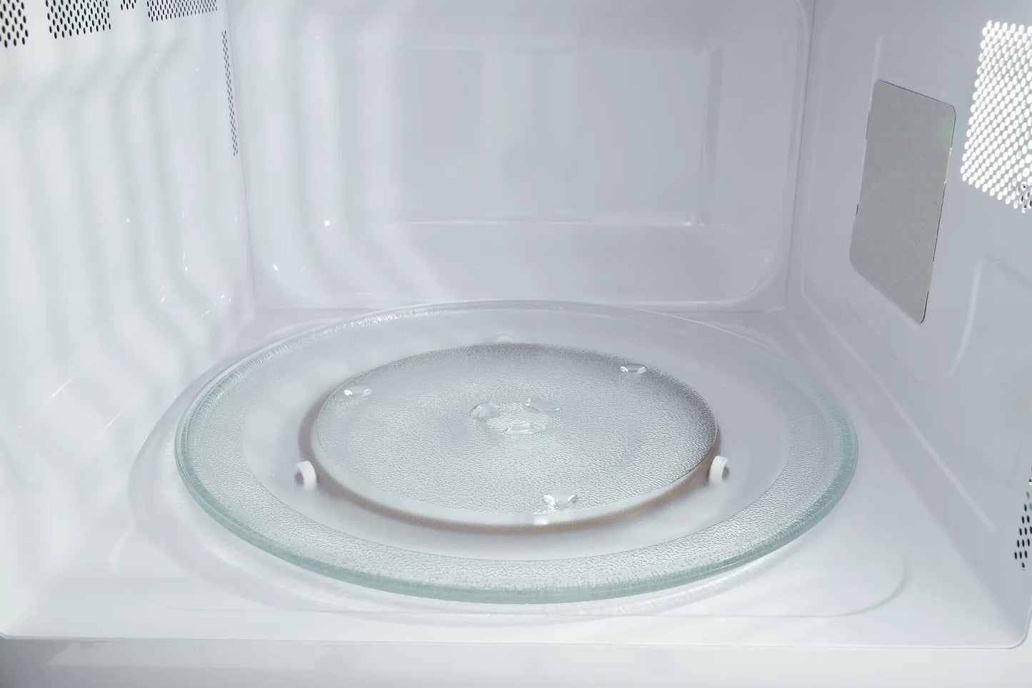 Interior view of a built-in microwave with clear glass turntable and white interior from kitchen appliances collection