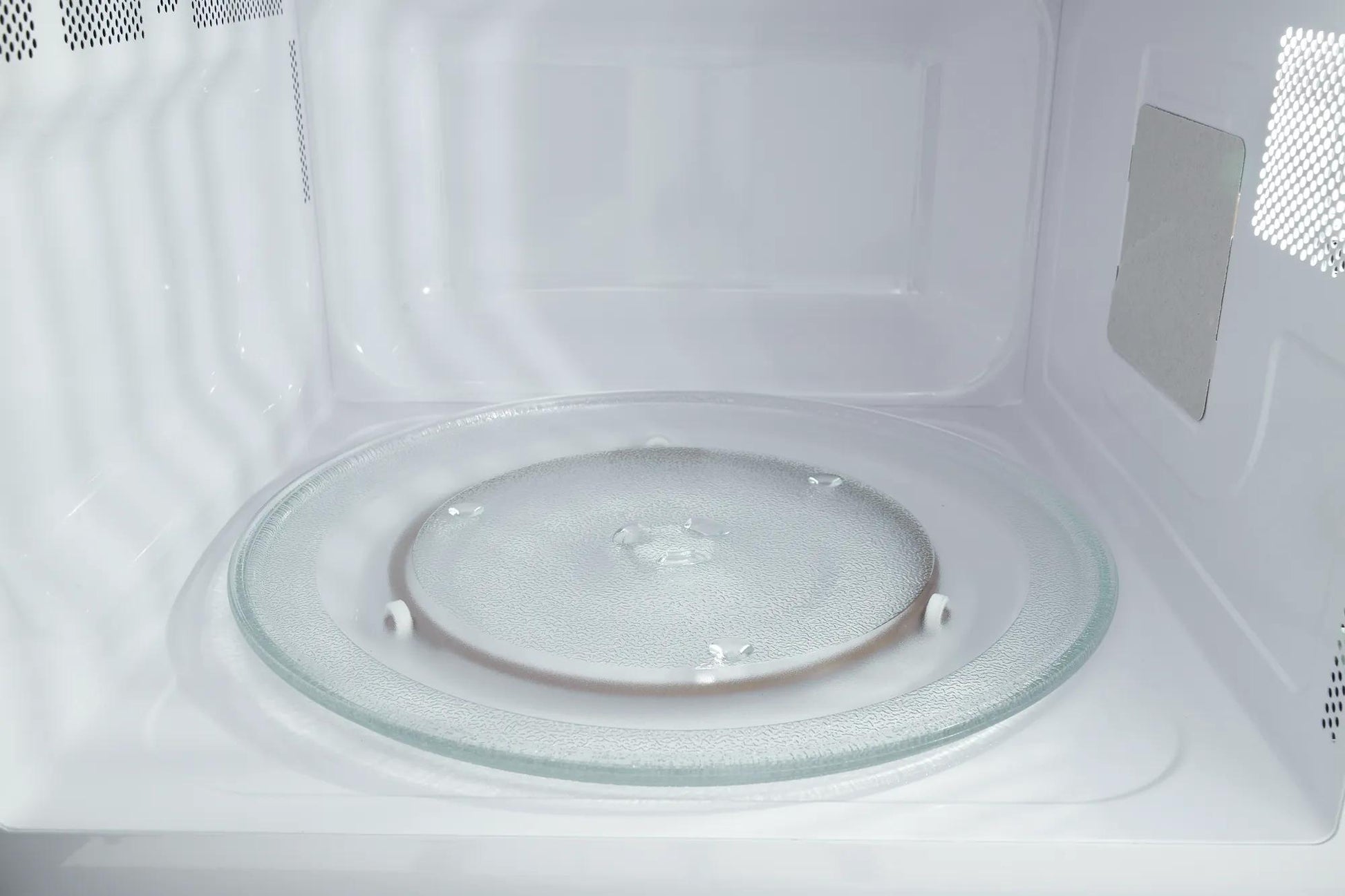 Interior view of a built-in microwave with clear glass turntable and white interior from kitchen appliances collection
