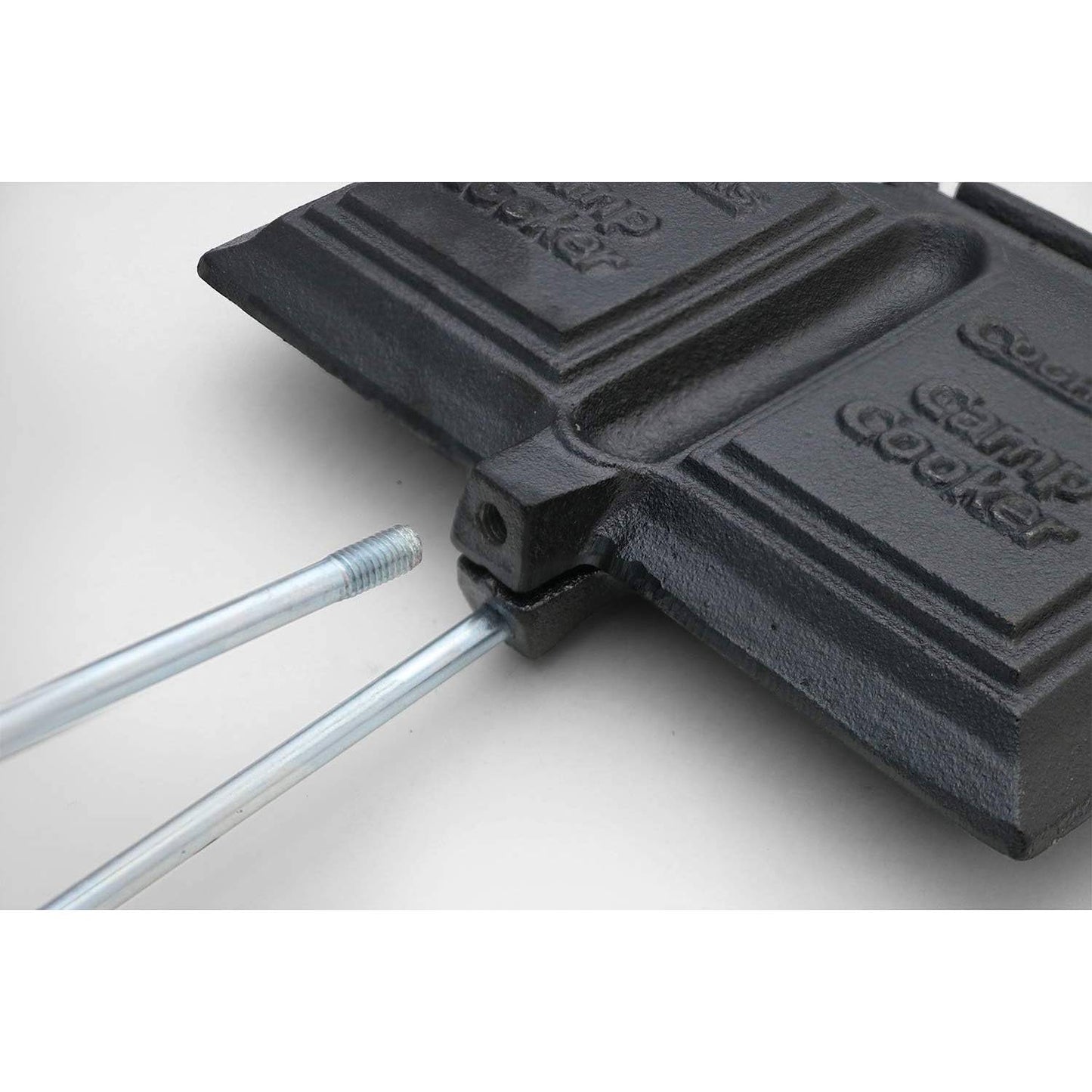 Close-up of black cast iron double sandwich cooker with metal handles for outdoor cooking and campfire use