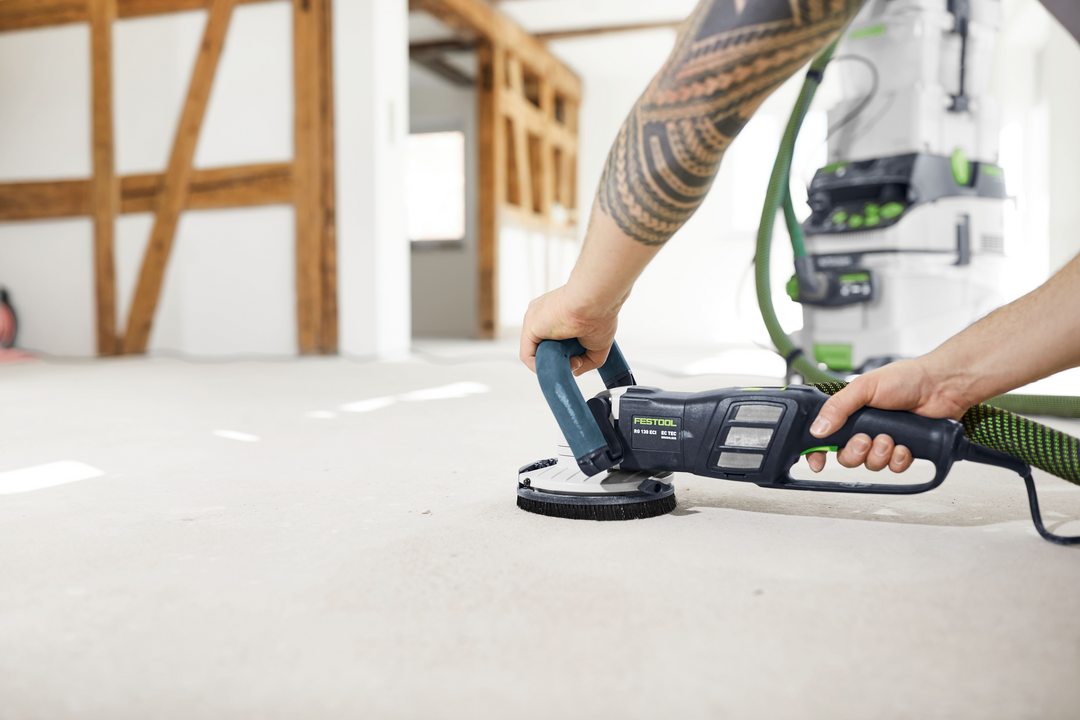 Person using a Festool diamond grinder with dust extraction smoothing a floor surface for home improvement tasks