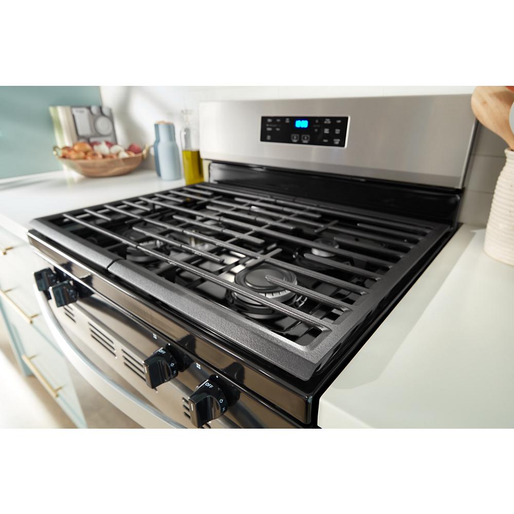 Close-up of stainless steel 30-inch gas range with black burner grates and digital control panel in kitchen setting