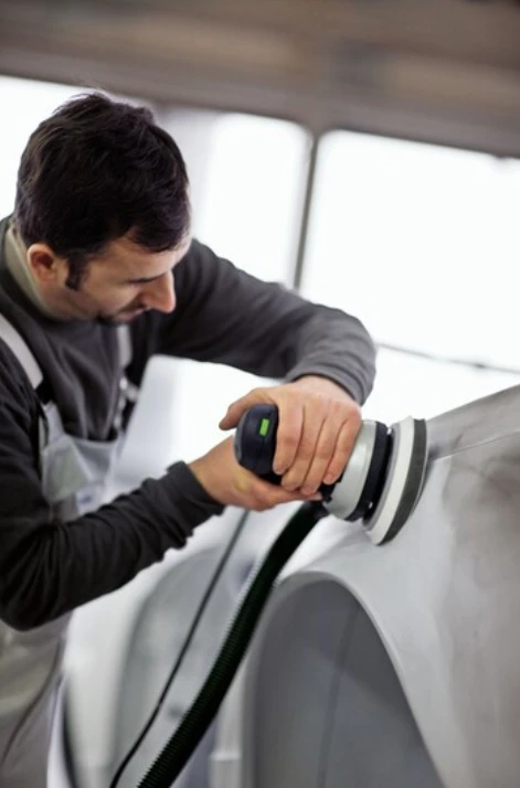 Man using a handheld Festool power tool with soft interface pad on vehicle surface for woodworking accessories