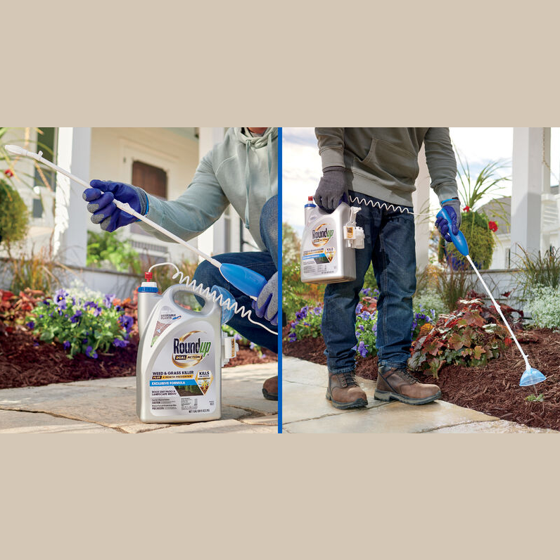 Gardener wearing gloves applying weed and grass killer with attached sprayer wand in landscaped garden area