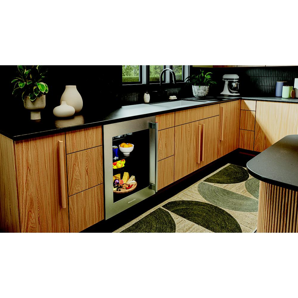 Undercounter refrigerator with glass door showcasing snacks and drinks integrated into modern kitchen cabinetry and decor