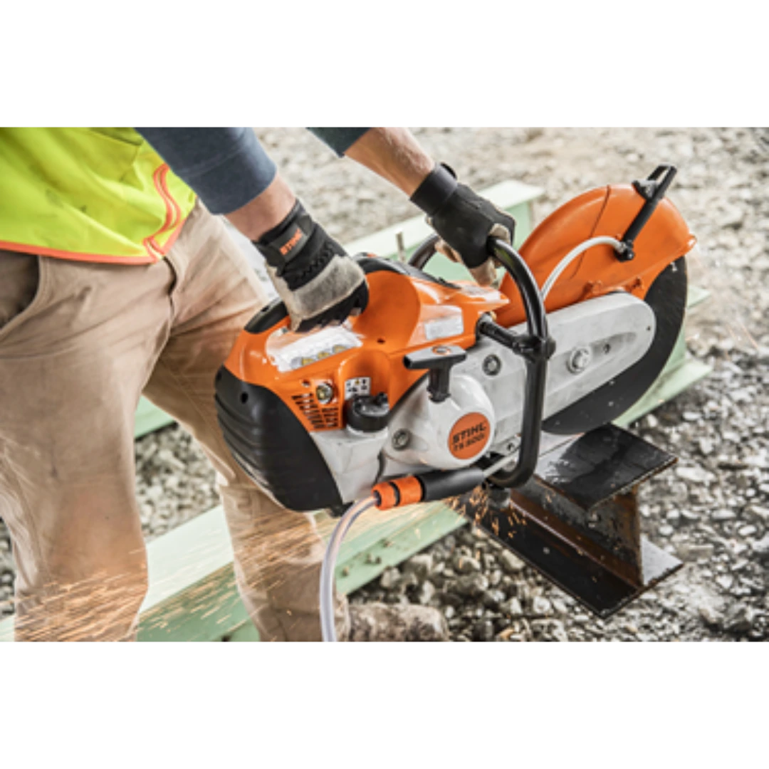 Worker using an orange power cutter with water hose attachment to cut metal beam on construction site for home improvement