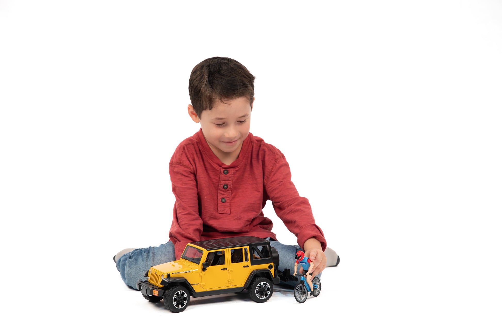 Child playing with Bruder yellow Jeep Wrangler Rubicon Unlimited toy and cyclist from Vehicles & Remote Controlled Toys collection