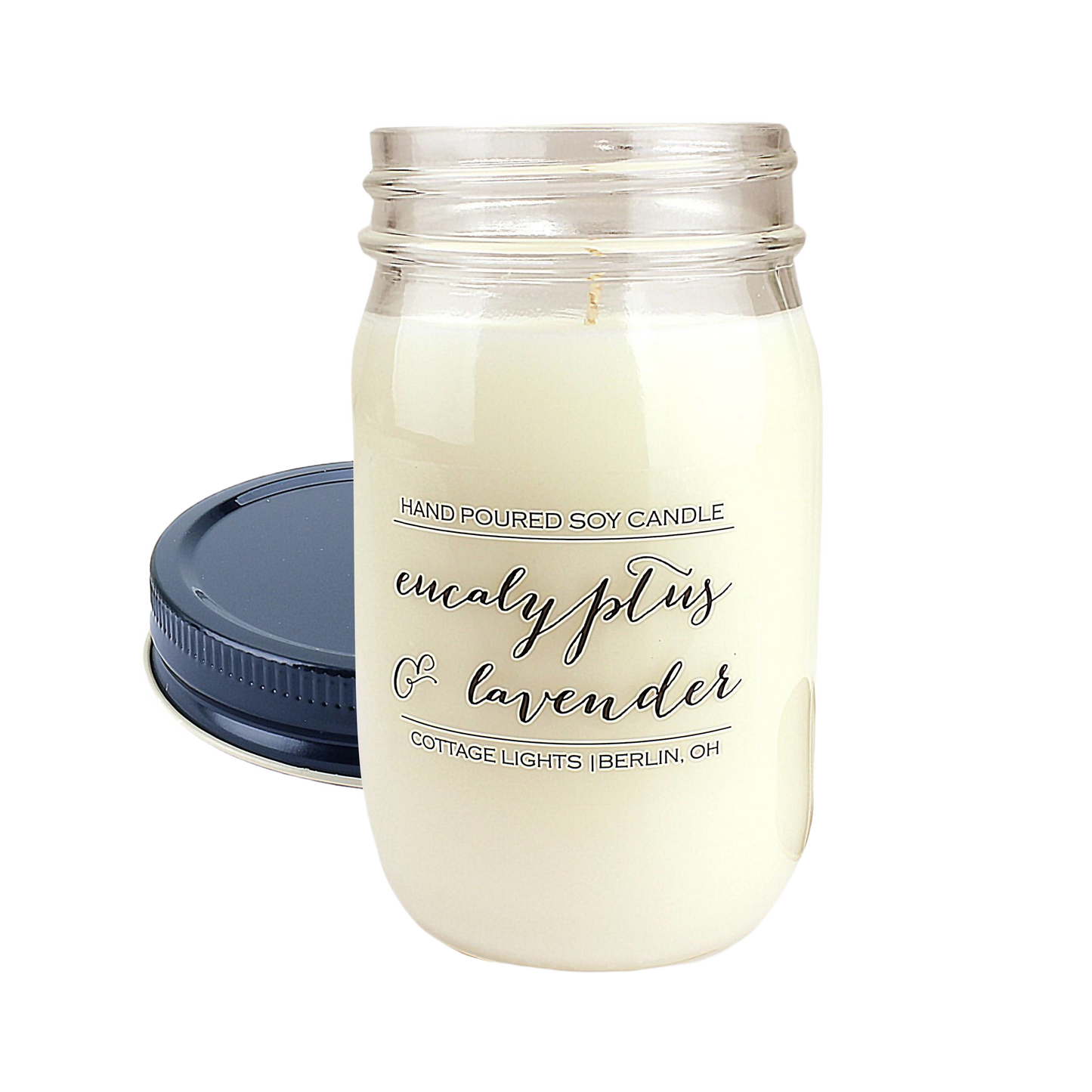 Clear glass jar candle with white soy wax labeled eucalyptus and lavender with a dark blue lid beside it