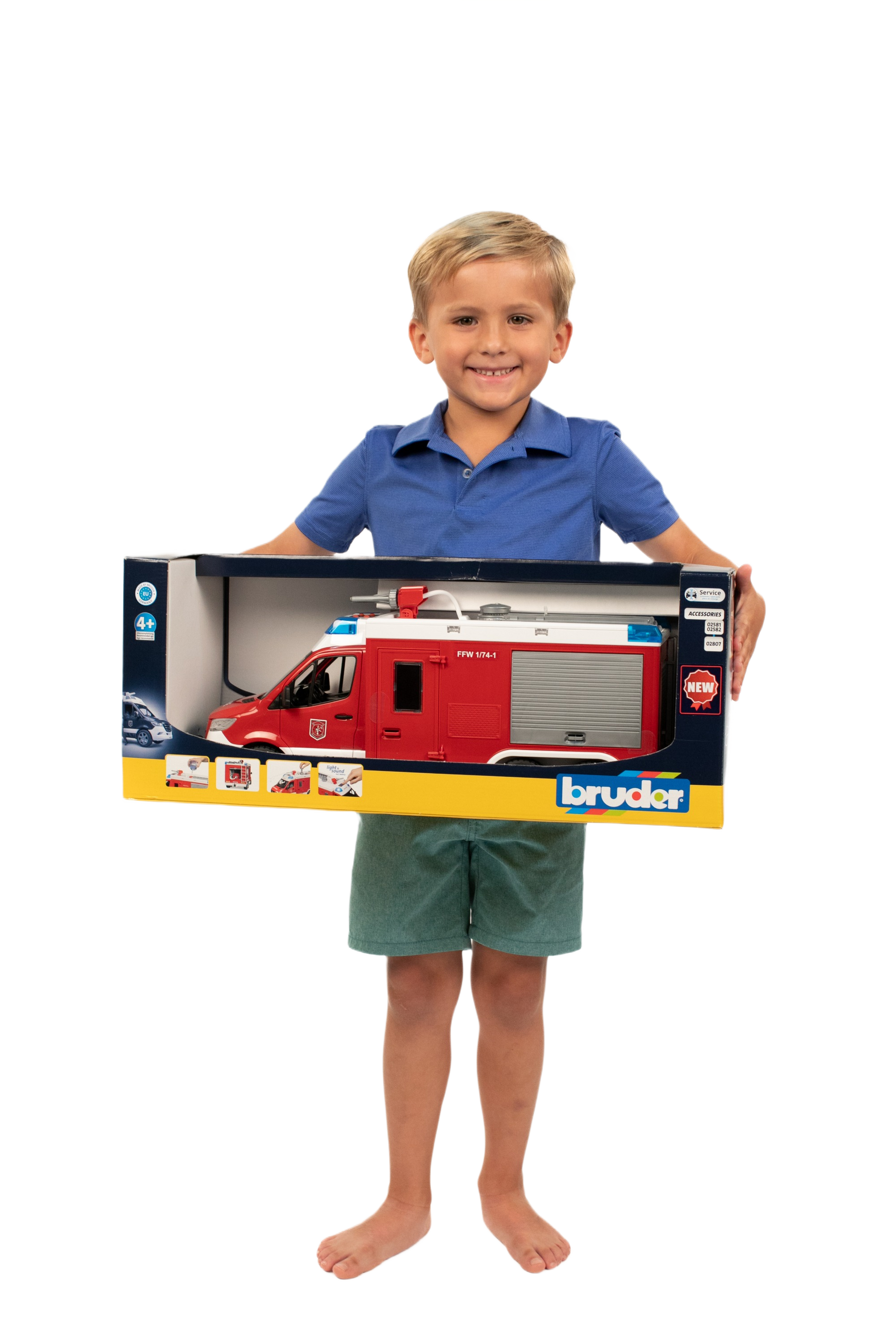 Child holding a boxed red Bruder MB Sprinter fire engine toy featuring side compartment and roof details