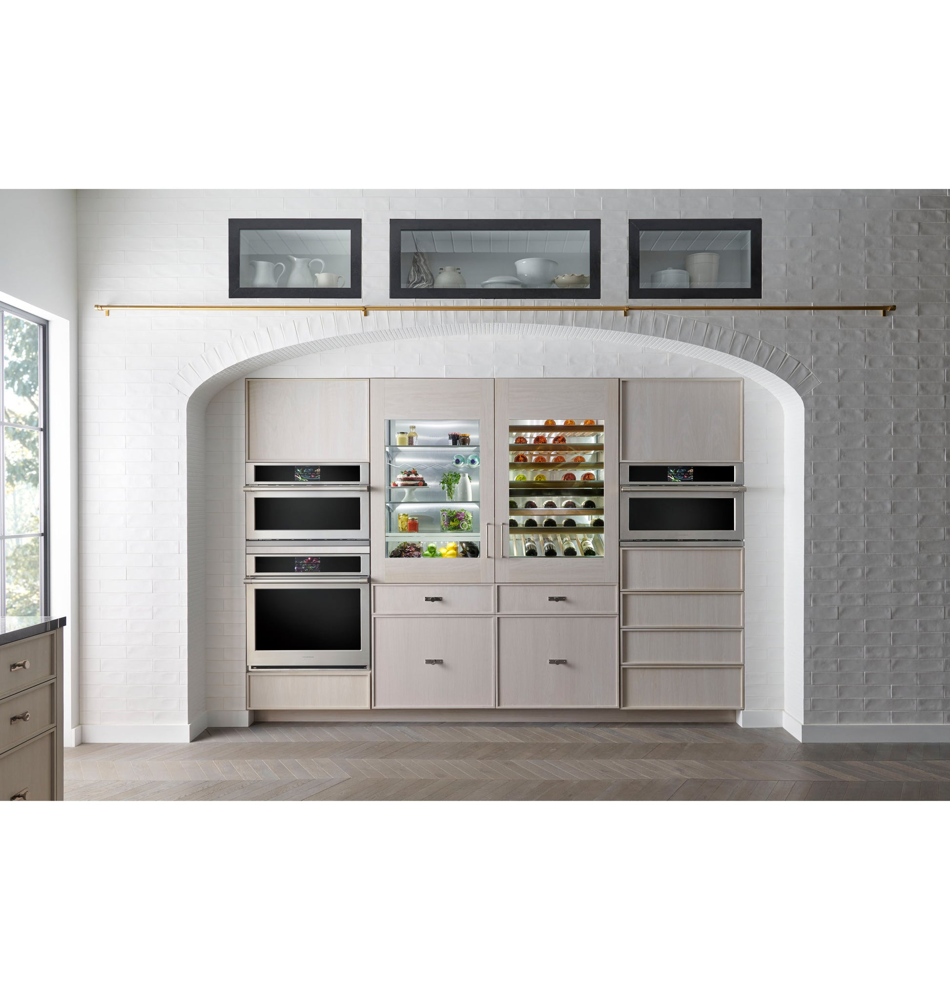 Built-in wall oven and refrigerator combination in light wood cabinetry within modern kitchen space with decorative shelving above