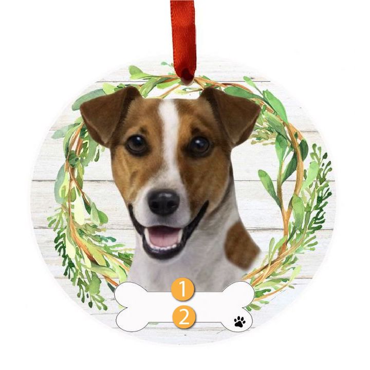 Round ornament with a smiling Jack Russell dog face inside a green leafy wreath and red hanging ribbon